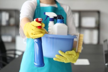 Modern ofiste plastik bir leğen ve temizlik malzemesi tutan kadın hademe.