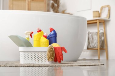 Banyoda küvetin yanında yerde temizlik malzemeleri olan plastik sepet, yakın çekim.