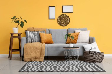 Gri kanepesi ve kahve masasında çiçekleri olan şık bir oturma odası.