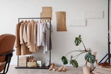 Moda stüdyosunun içinde giysi askılığı ve palmiye bitkisi var.