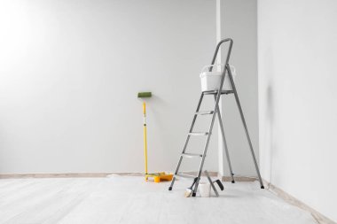 Boyacı aletleri olan metal bir merdiven. Odada ışık duvarı var.