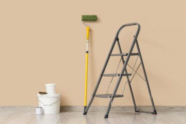 Boya kutularıyla bej duvarın yanında merdiven var.