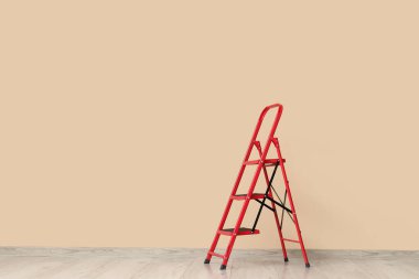 Bej duvarın yanındaki kırmızı merdiven.