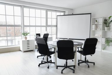 Boş projektör ekranı ve masası olan konferans salonunun içi