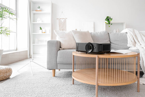Modern projector on table in living room interior