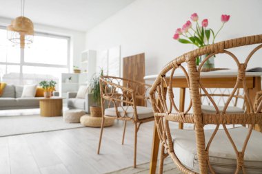 Modern stüdyo dairede yemek masasının yanındaki hasır sandalye, yakın plan.