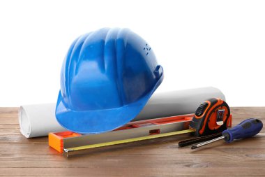 Katı şapka, plan ve inşaat araçları beyaz arka plana karşı ahşap masa üzerinde