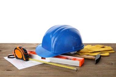 Sert şapka, ev planı ve inşaat aletleri beyaz arka plana karşı ahşap masa üzerinde