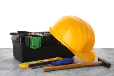 Beyaz arka plana karşı grunge tablo üzerindeki sert şapka, araç kutusu ve inşaat araçları