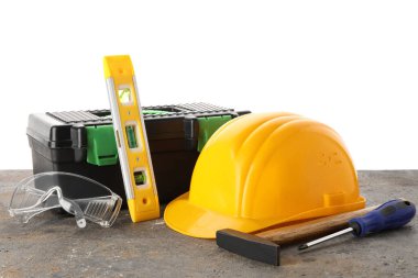 Beyaz arka plana karşı grunge tablo üzerindeki sert şapka, araç kutusu ve inşaat araçları