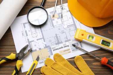 Sert şapka, ev planı ve ahşap arka planda inşaat araçları