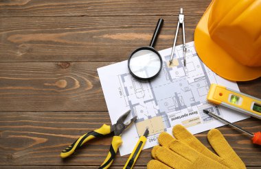 Sert şapka, ev planı ve ahşap arka planda inşaat araçları