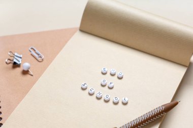 Renk arkaplanı üzerinde OKULU metni ve kırtasiye malzemesi içeren defter, kapat