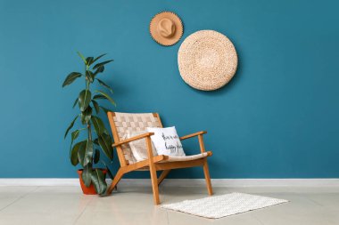 Oturma odasında mavi duvarın yanında bitkisi olan tahta koltuk.