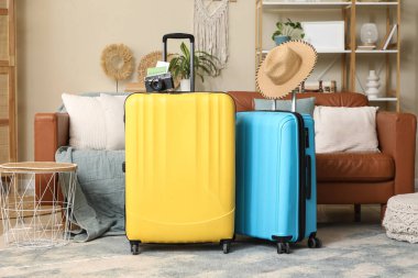 Oturma odasında şapka ve fotoğraf makinesi olan bavullar.