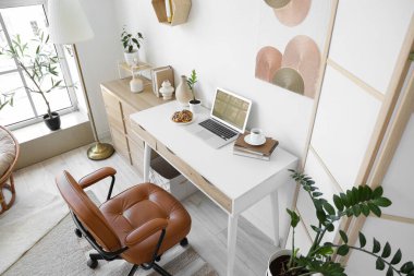 Ev ofisinde dizüstü bilgisayarı, kurabiyesi ve kahve fincanı olan bir iş yeri.