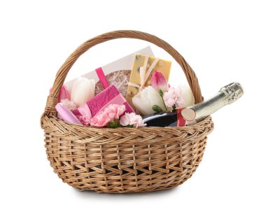 Beyaz arka planda şampanya, çiçek, tatlı ve rimel dolu bir sepet.