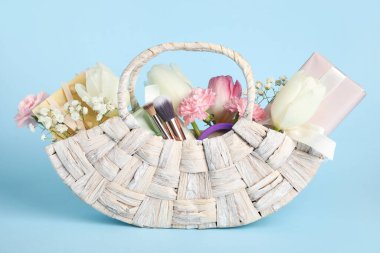 Arkaplanda hediye kutuları, güzel çiçekler ve kozmetik ürünlerle dolu bir sepet.