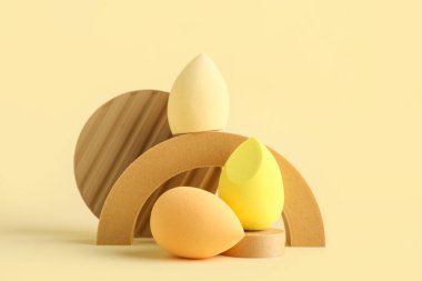 Sarı arka planda makyaj süngeri olan dekoratif podyumlar