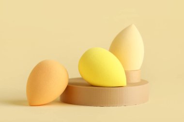 Sarı arka planda makyaj süngeri olan dekoratif podyumlar