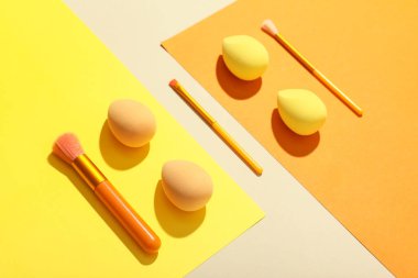 Renkli arkaplanda makyaj süngerleri ve fırçalar