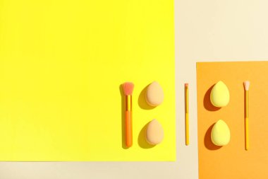 Renkli arkaplanda makyaj süngerleri ve fırçalar