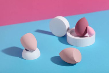 Renkli arka planda makyaj süngerleri olan dekoratif podyumlar