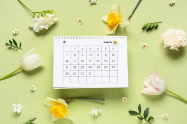 Mart ayının kağıt takvimi ve renk arkaplanındaki güzel bahar çiçekleriyle kompozisyon