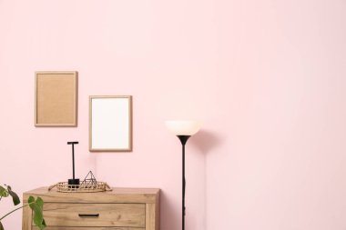 Odasında pembe duvarın yanında lambalar olan tahta çekmeceler.