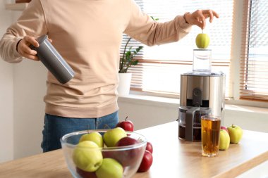 Genç adam mutfakta elma suyu yapıyor.