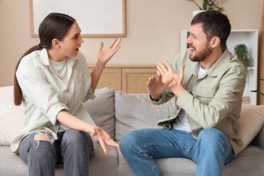 Kızgın genç çift evdeki kanepede tartışıyor.