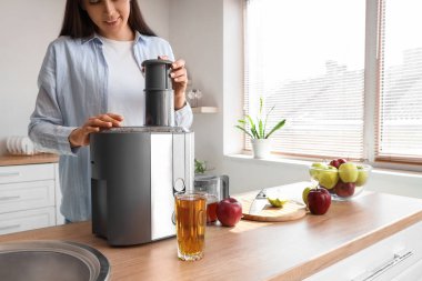 Genç kadın mutfakta elma suyu yapıyor.