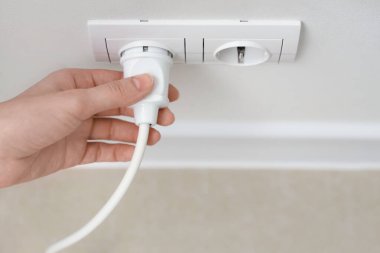 Kadın el prizden dışarı çıkıyor. Işık duvarında, yakın plan.