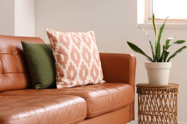 Oturma odasındaki yastıklı ve çiçekli kahverengi kanepe.