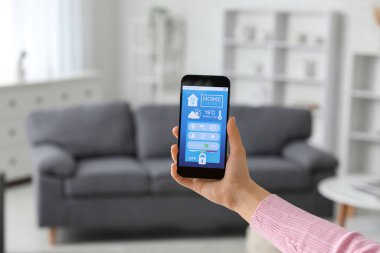 Akıllı ev güvenlik sistemi kontrol paneli olan cep telefonlu bir kadın.