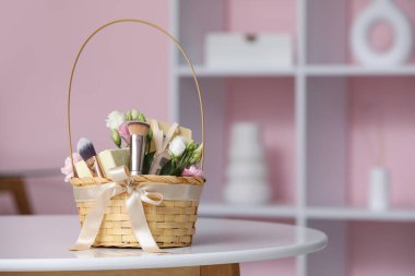 Kozmetik ürünler, hediye kutuları ve oturma odasındaki çiçeklerle dolu bir sepet.