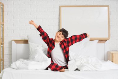 Evde pijamalı, yatakta esneyen tatlı bir çocuk.