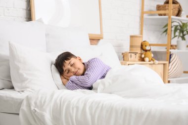 Çizgili pijamalı tatlı çocuk evde yatakta uyuyor.
