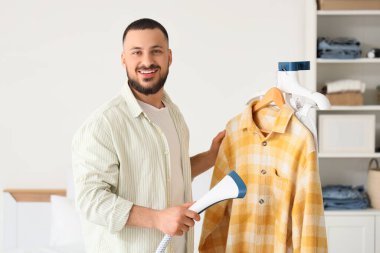 Buharlı ve gömlekli genç adam yatak odasında.