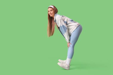 Yeşil arka planda bahar kıyafetleri içinde şık genç bir kadın.