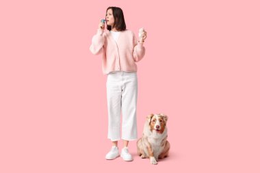 Pembe arka planda astım spreyi olan köpek ve genç bir kadın. Kürke alerji