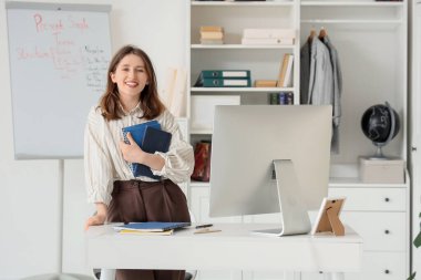 Not defterleri olan bayan öğretmen evde İngilizce dersi veriyor.