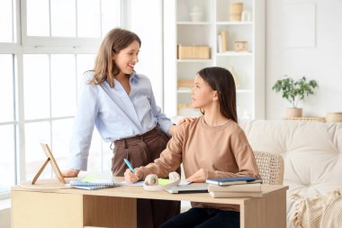 Genç kız evde öğretmeniyle ders çalışıyor.