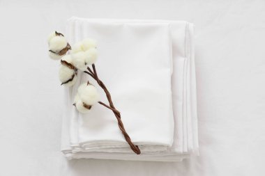 Yatağında pamuk çiçekleri olan beyaz çarşaf yığını.