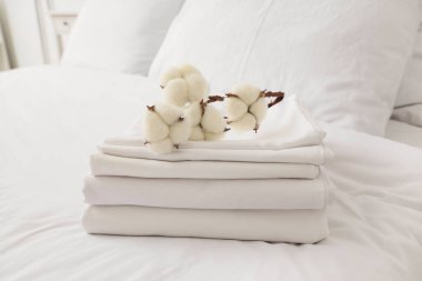 Yatağında pamuk çiçekleri olan temiz beyaz çarşaf yığını.