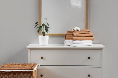 Pamuk çiçekli çarşaflar ve yatak odasındaki çekmecelerin üzerine bitki.