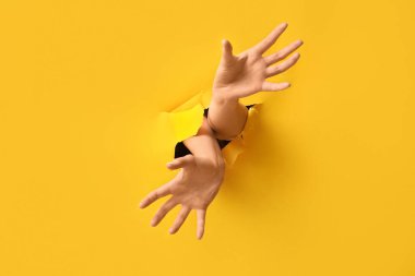 Sarı kağıttaki delikten görünen kadın elleri