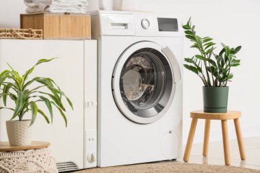 Çamaşır odasının içinde modern çamaşır makinesi ve çamaşır kurutma makinesi beyaz duvarın yanında.