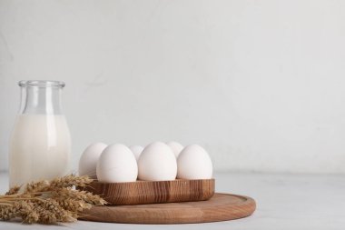 Taze tavuk yumurtası, bir şişe süt ve buğday dikenli tahta tutacağı.