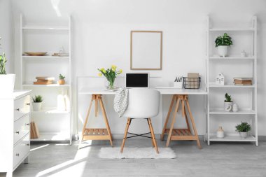 Çalışma yeri, çiçekler ve raf üniteleri olan hafif ofisin içi